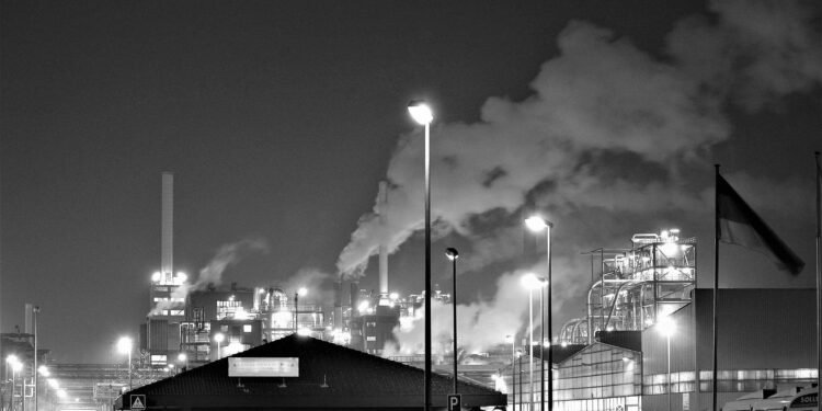 A monochrome view of an industrial factory emitting smoke at night in Hürth, Germany. Climate Change: What Does It Mean for Us?