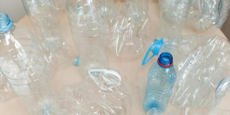 Top view of empty plastic bottles arranged on a light wooden surface, emphasizing recycling. Circular Economy: Recycling for a Sustainable World