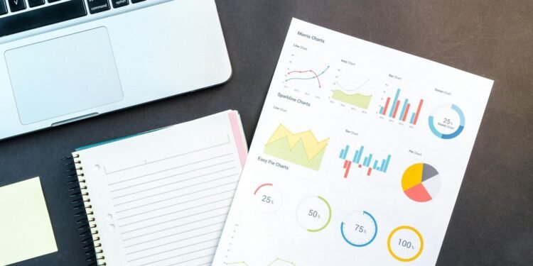 Flatlay of business report with colorful charts, a notebook, and a laptop for data analysis on a desk. Discover the top sales tools that enhance productivity, improve communication, and drive revenue for businesses.